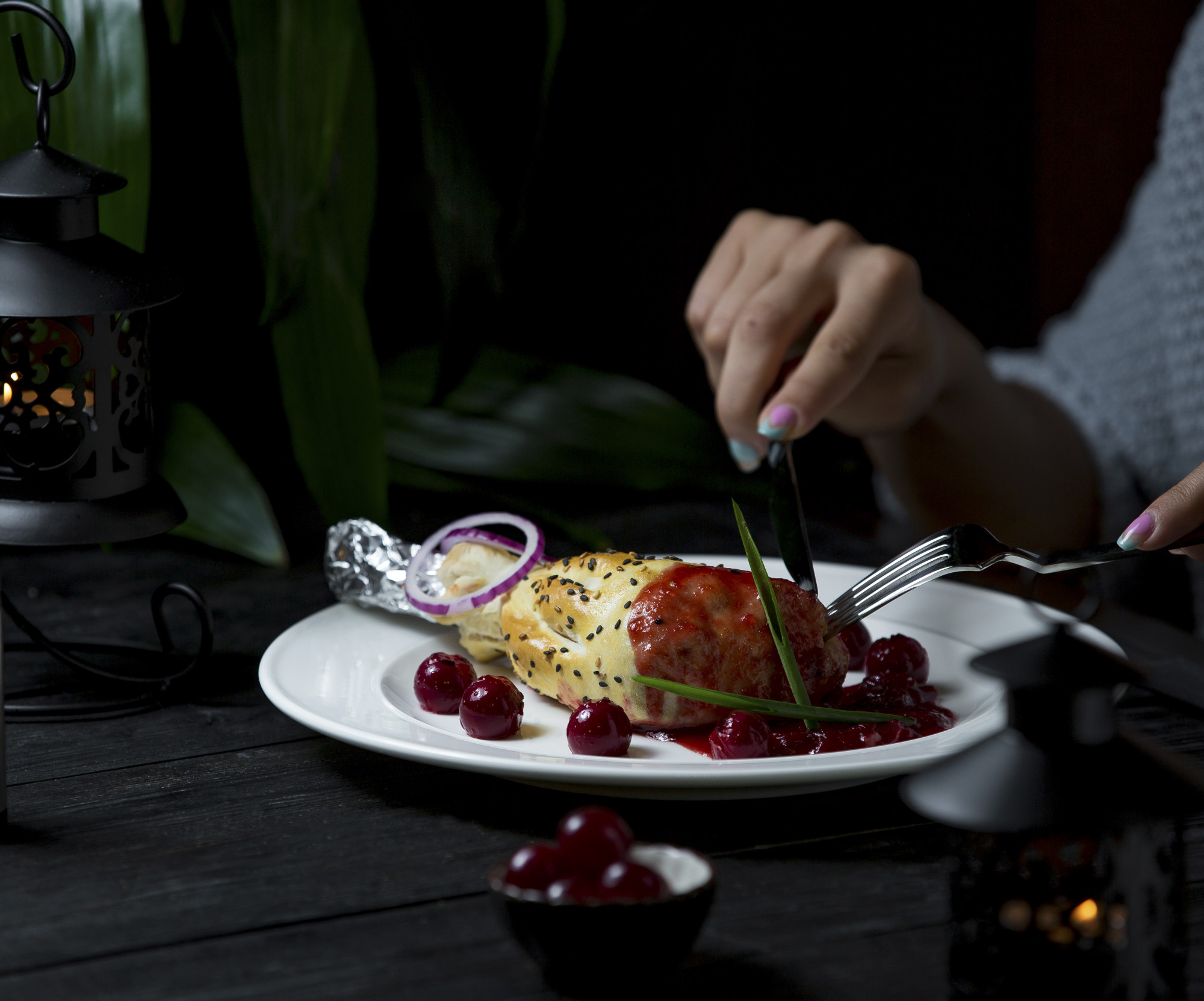 Chef plating a refined dish on dark table